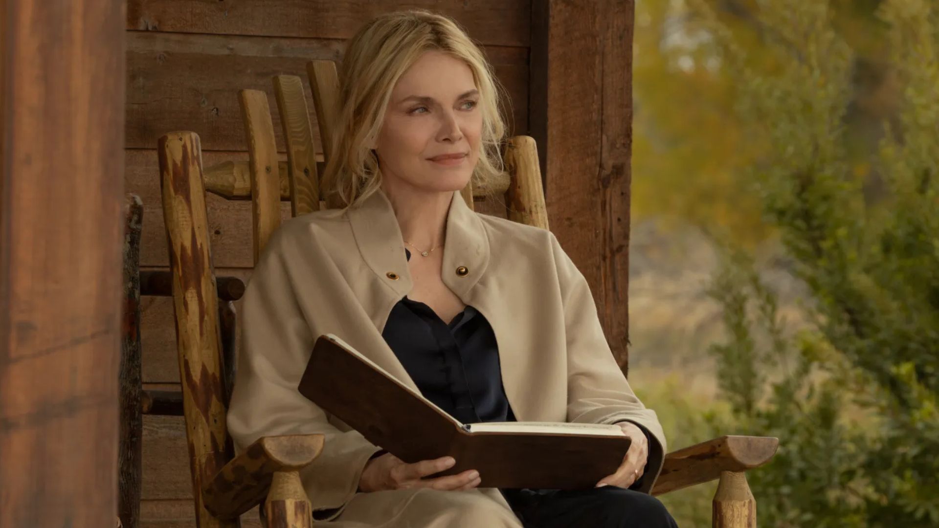 Michelle Pfeiffer sits in a rocking chair and holds a book