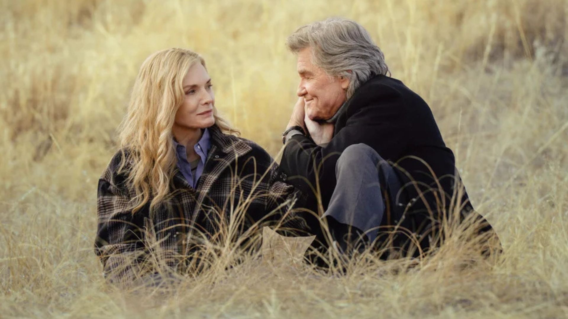 Michelle Pfeiffer and Kurt Russell are sitting in the middle of a field