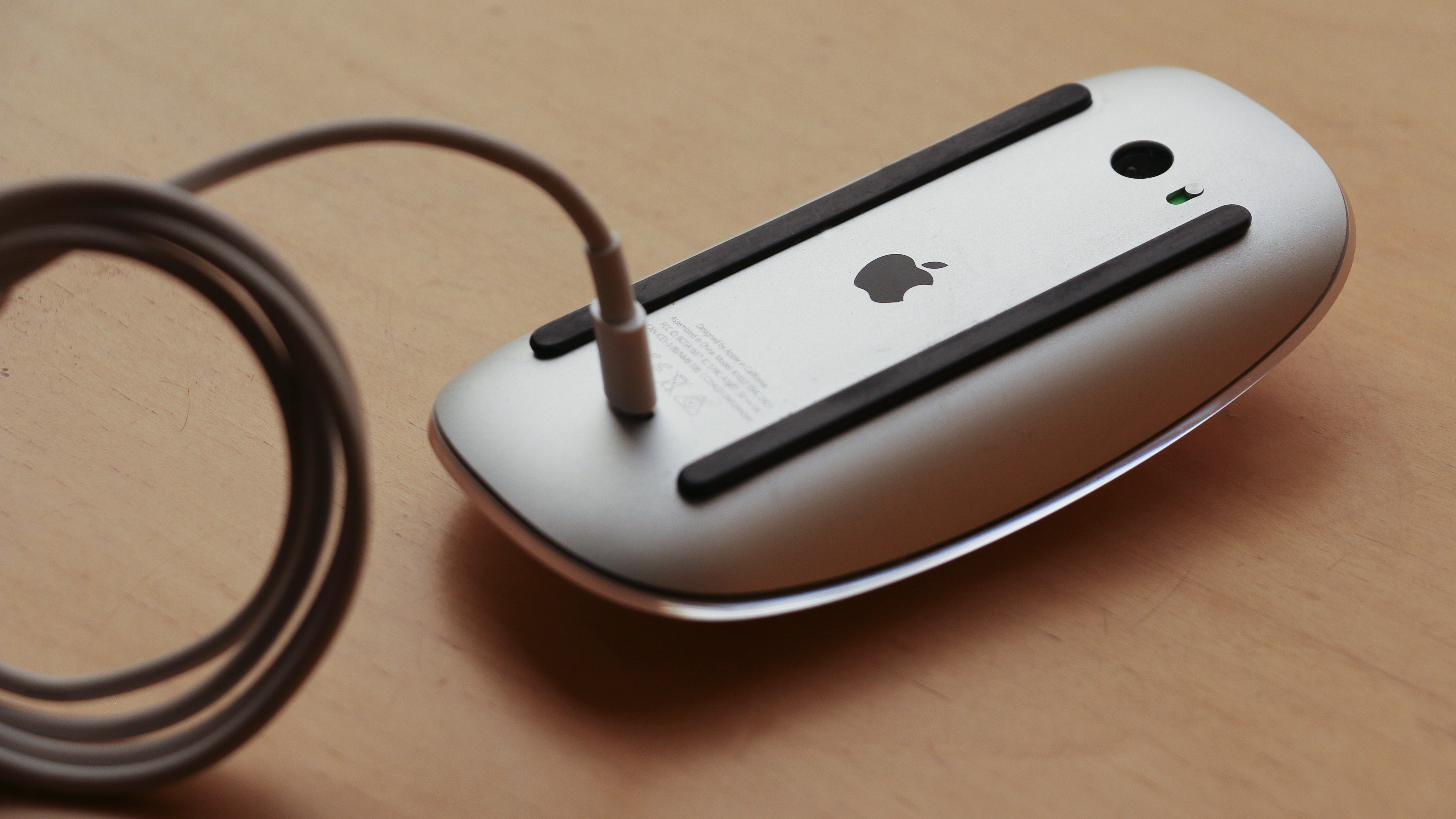 An Apple Magic Mouse on an upside down table is being charged