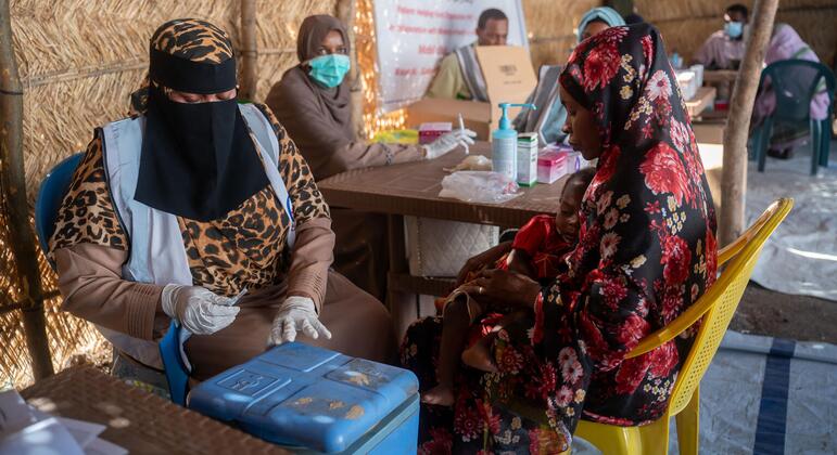 A woman holds a child as she receives medical attention at a UNICEF-supported health center in Sudan's Kordofan region, where families have fled violence.
