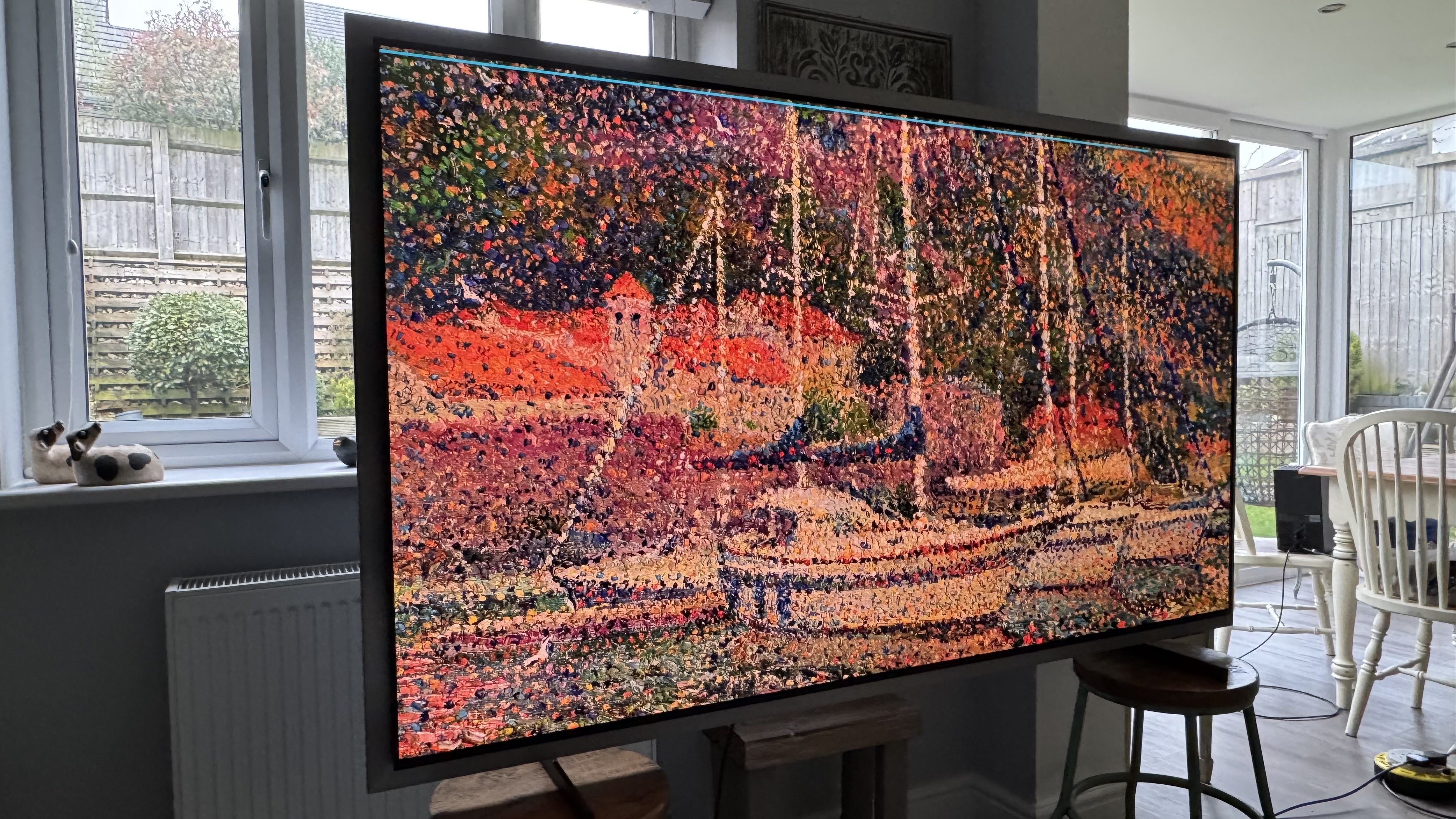Samsung S99H/S95H TV in a home showing artwork of a boat on the screen in an impressionistic style