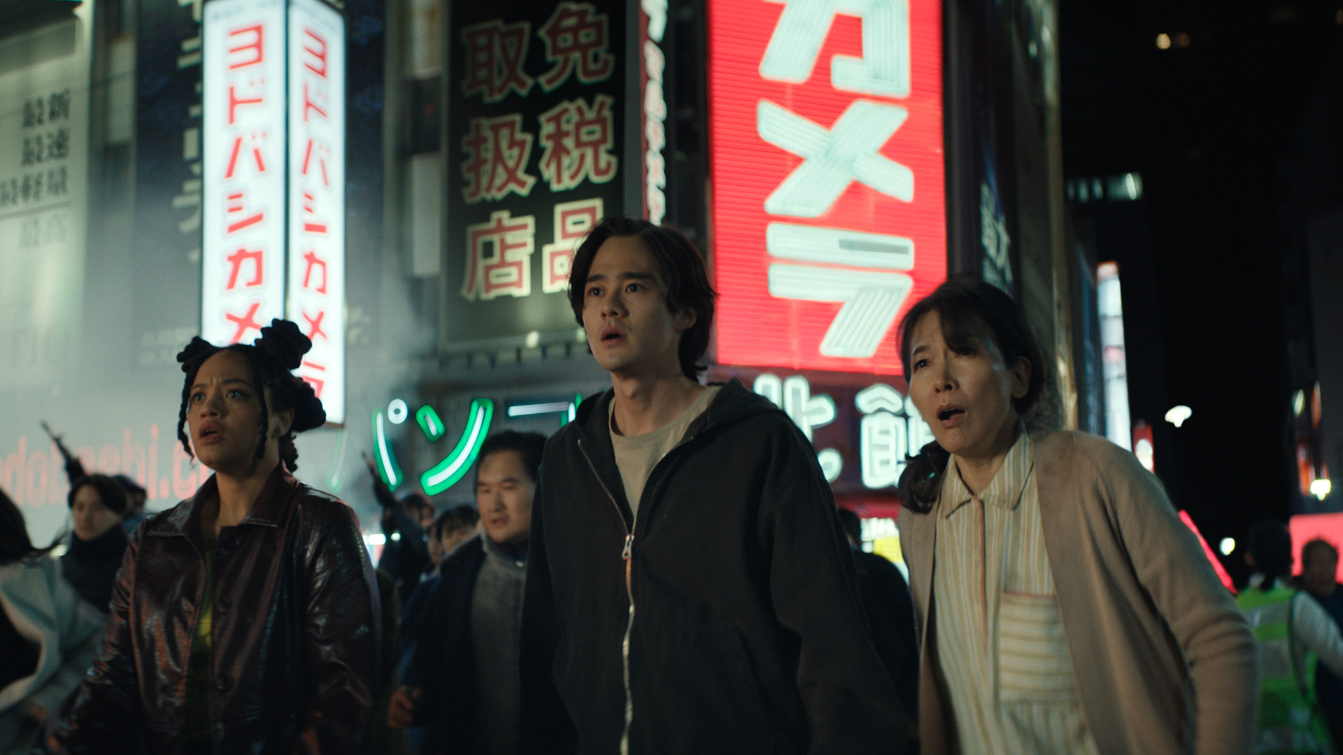 May and Kentaro stand on a crowded street at night looking shocked in Monarch: Legacy of Monsters Season 2 Episode 6