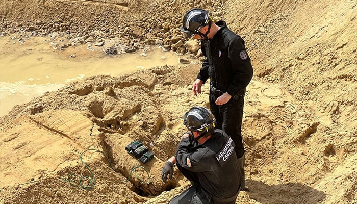 This undated handout photo provided by the Prefecture de Police on April 19, 2026 shows members of the police's Explosive Ordnance Unit (EOD) working to neutralize a World War II bomb partially uncovered near a residential area in the northwestern Paris suburb of Colombes. — AFP