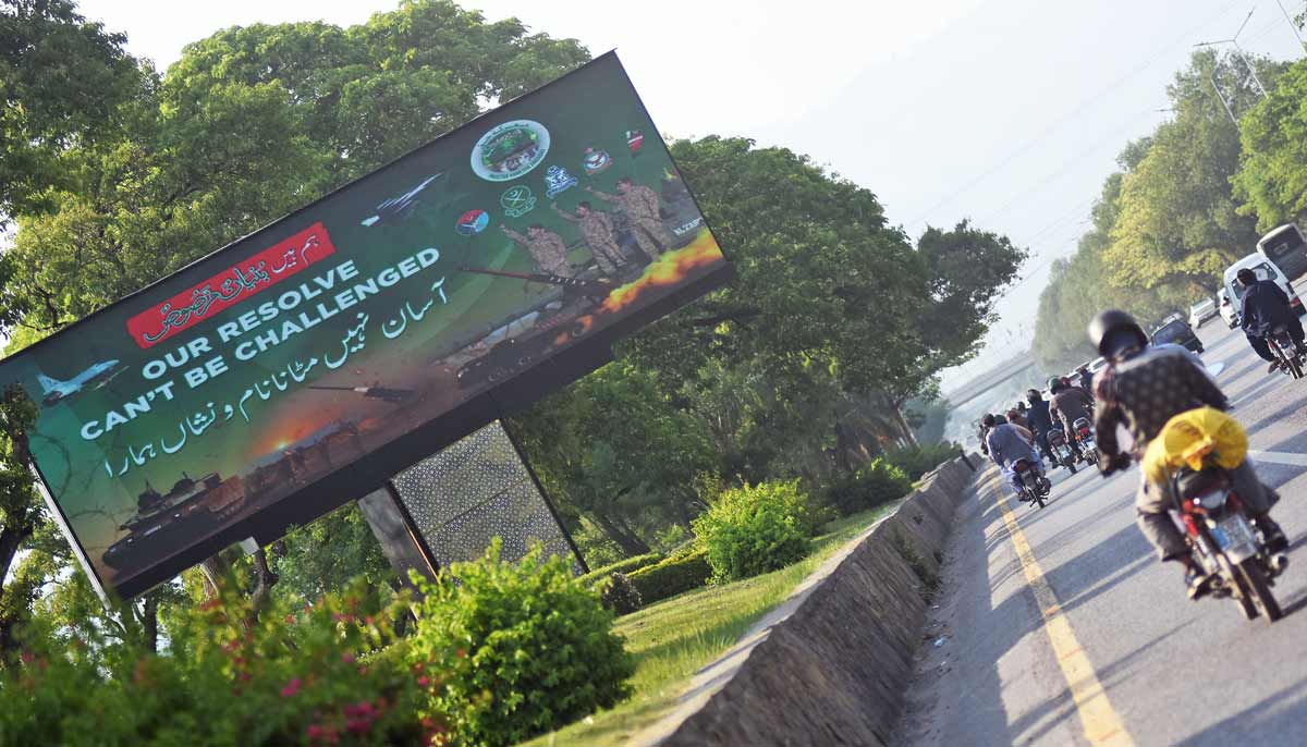 Commuters move past a roadside digital billboard at a green belt along the Islamabad Expressway in the federal capital as Pakistan marks the one year anniversary of Operation Bunyan-un-Marsoos - Online
