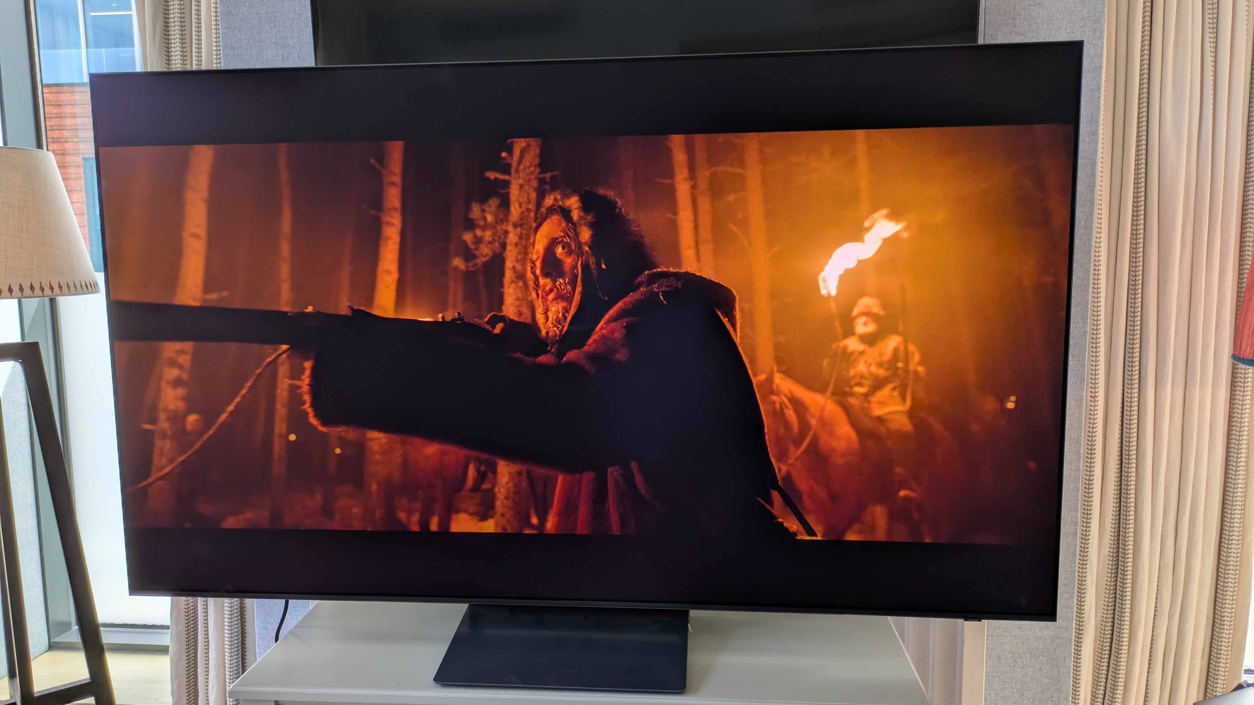 Samsung S90H OLED TV with man holding a gun from The Revenant on the screen