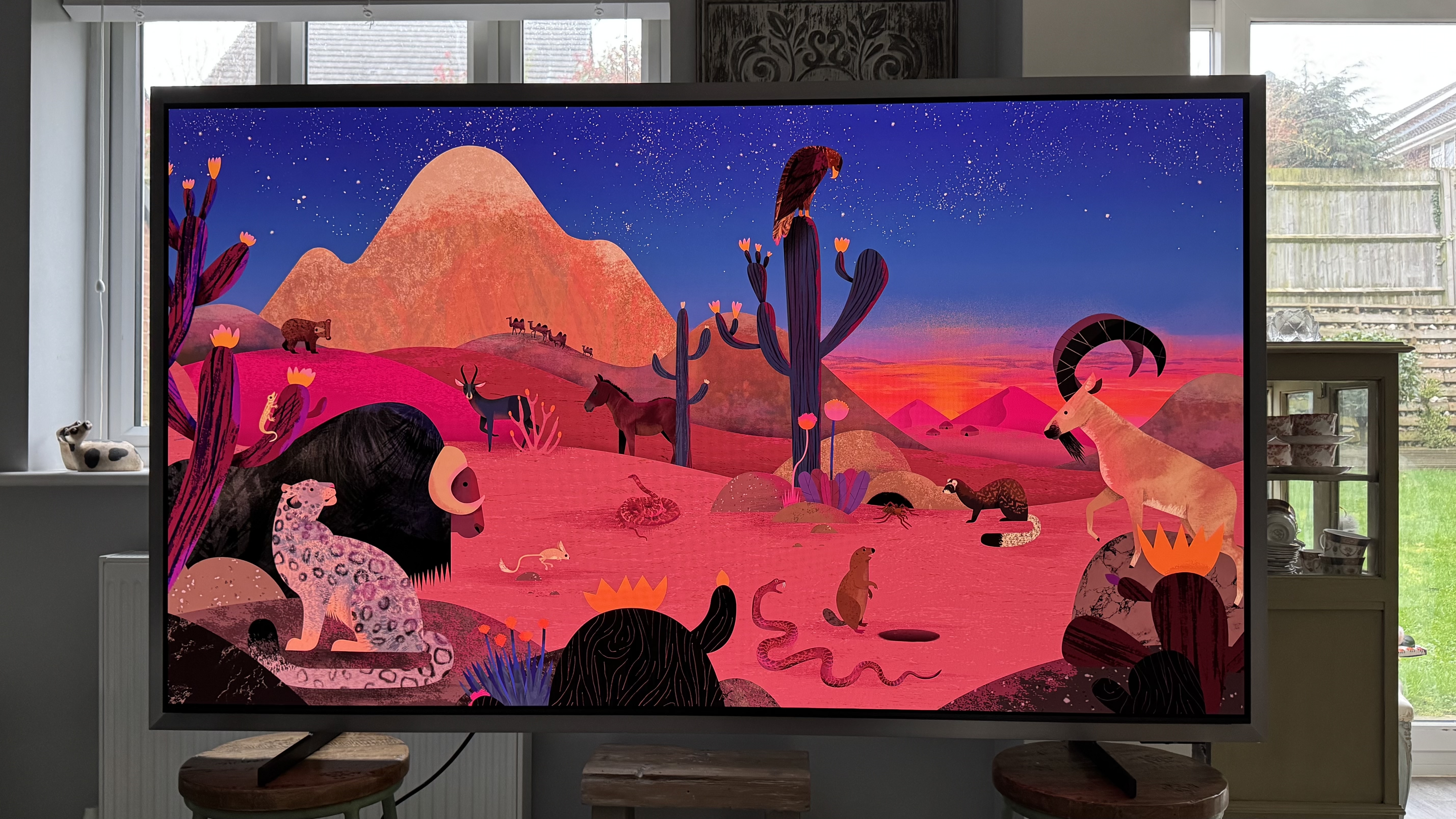 The Samsung S99H/S95H TV in a home showing an abstract image of a desert scene on the screen showing its strong colors