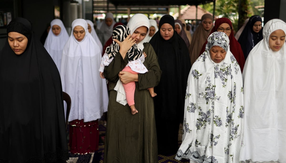 A Muslim woman carries a small child as she performs Eid ul Adha mass prayers at a mosque in Ampang, Malaysia, May 27, 2026. — Reuters