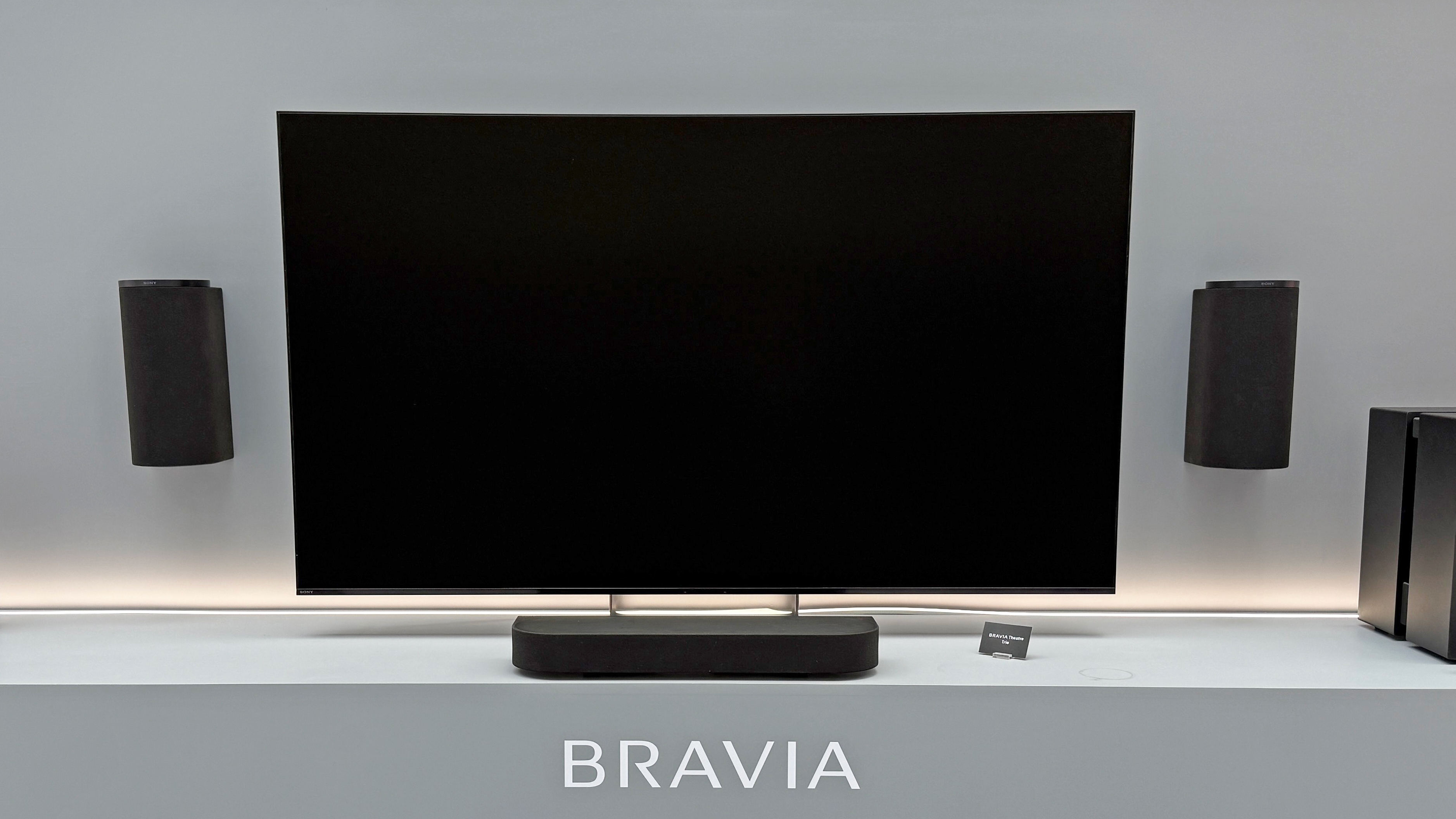 Sony Bravia Theater Trio with black TV screen. Two speakers hang on the wall, either side of a TV with a small speaker below