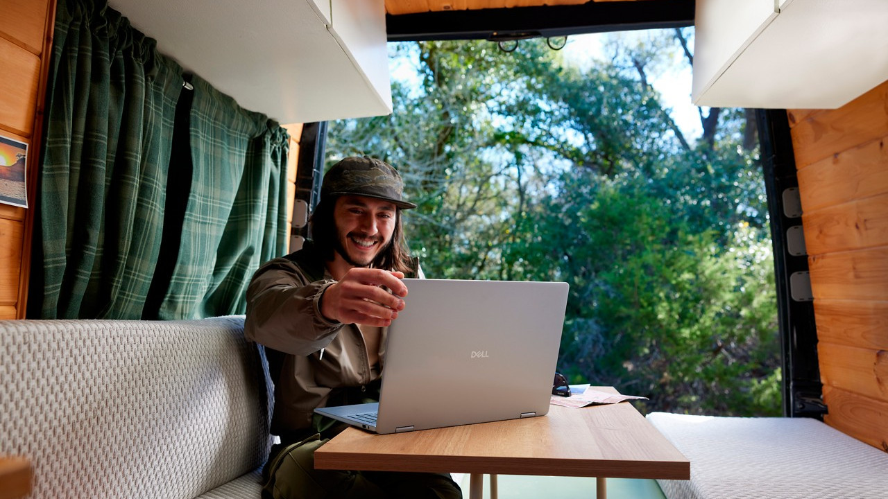 Dell Windows 11 laptop on a desk with a happy person looking at the screen