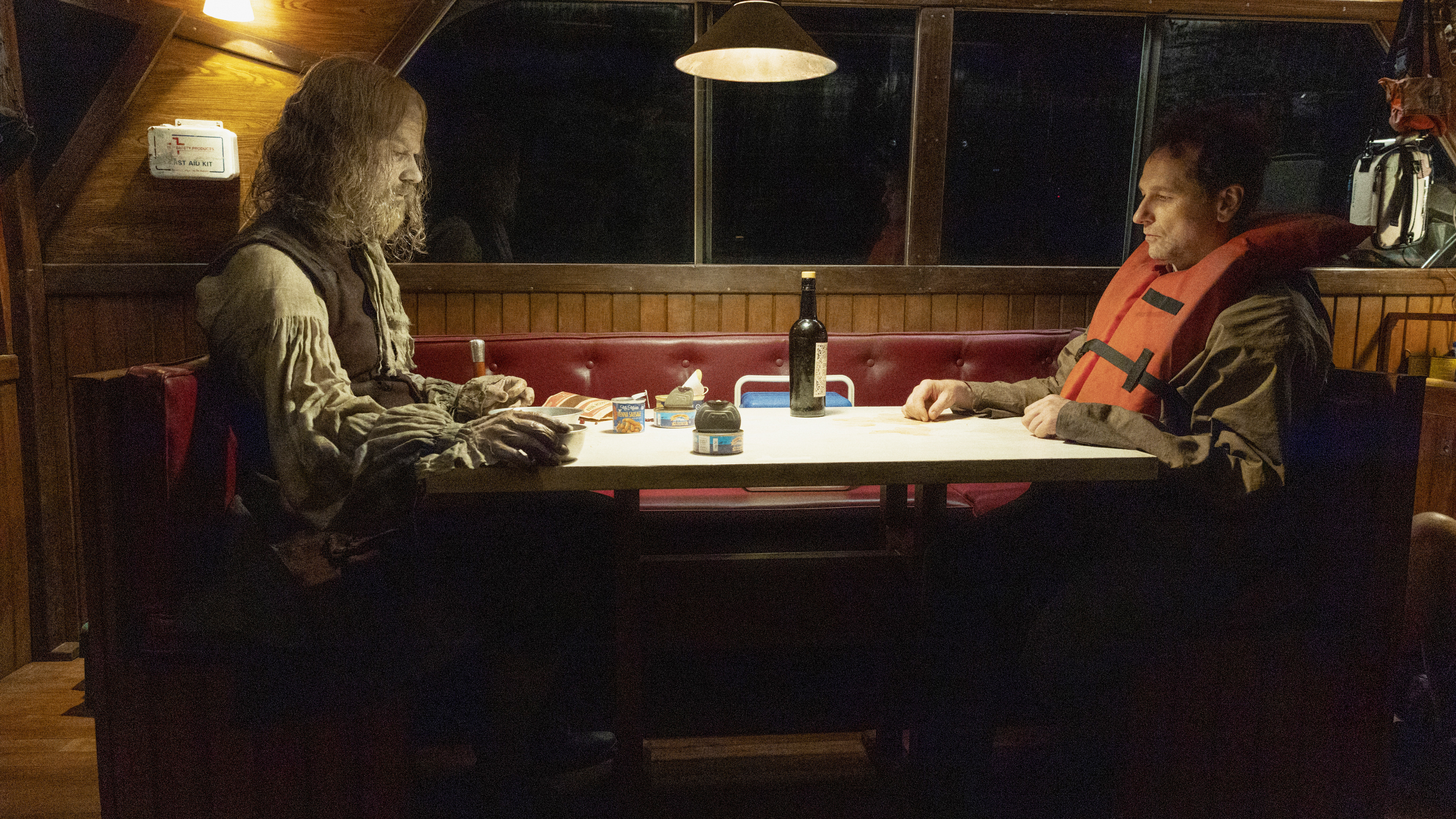 A zombified Richard Warren sits opposite Tom Loftis on a boat at night in Widow's Bay episode 7