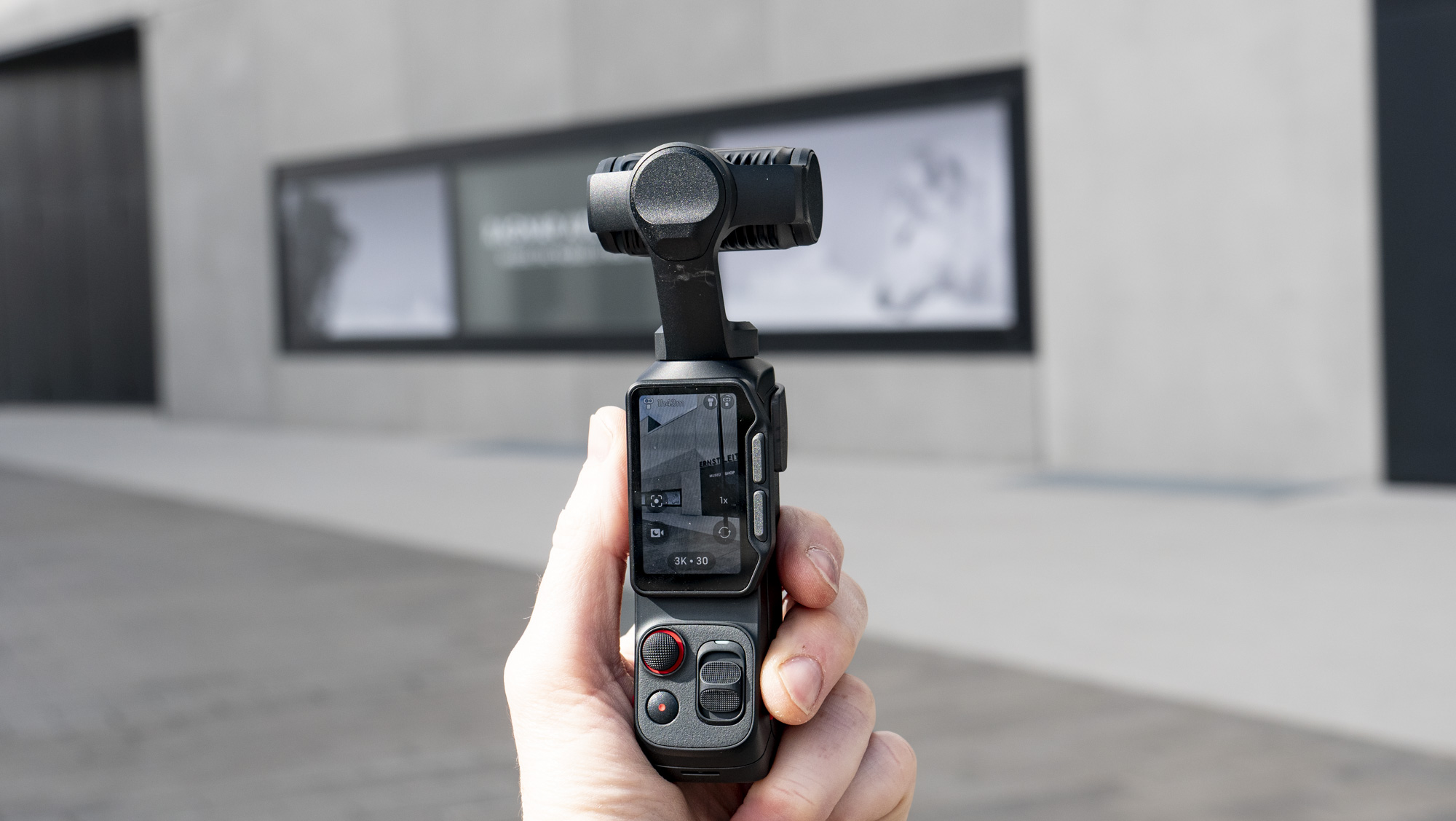 Insta360 Luna Ultra vlogging camera in hand, outdoors in a gray urban scene