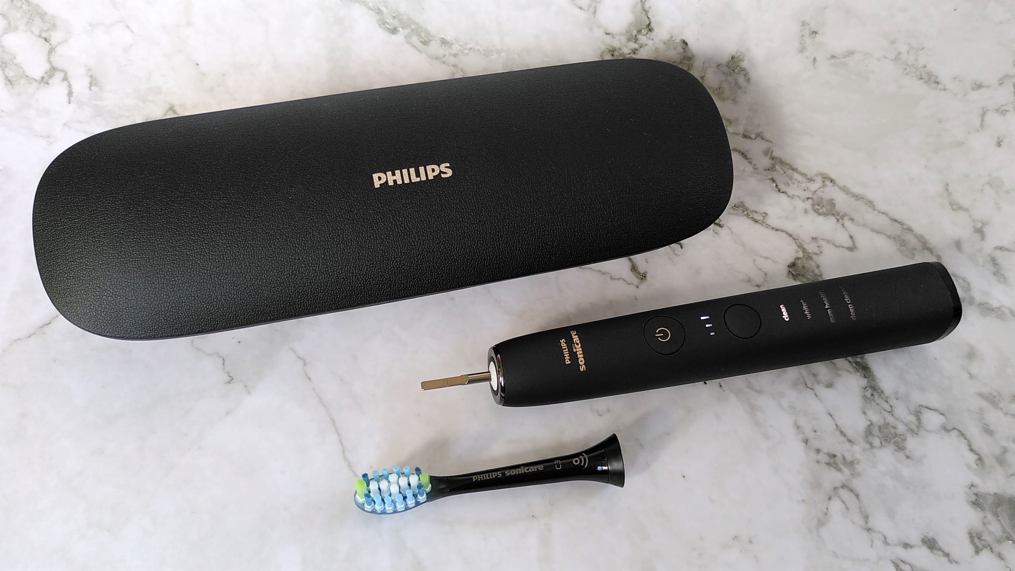 Philips Sonicare 9000 DiamondClean with brush head detached, next to the charging case