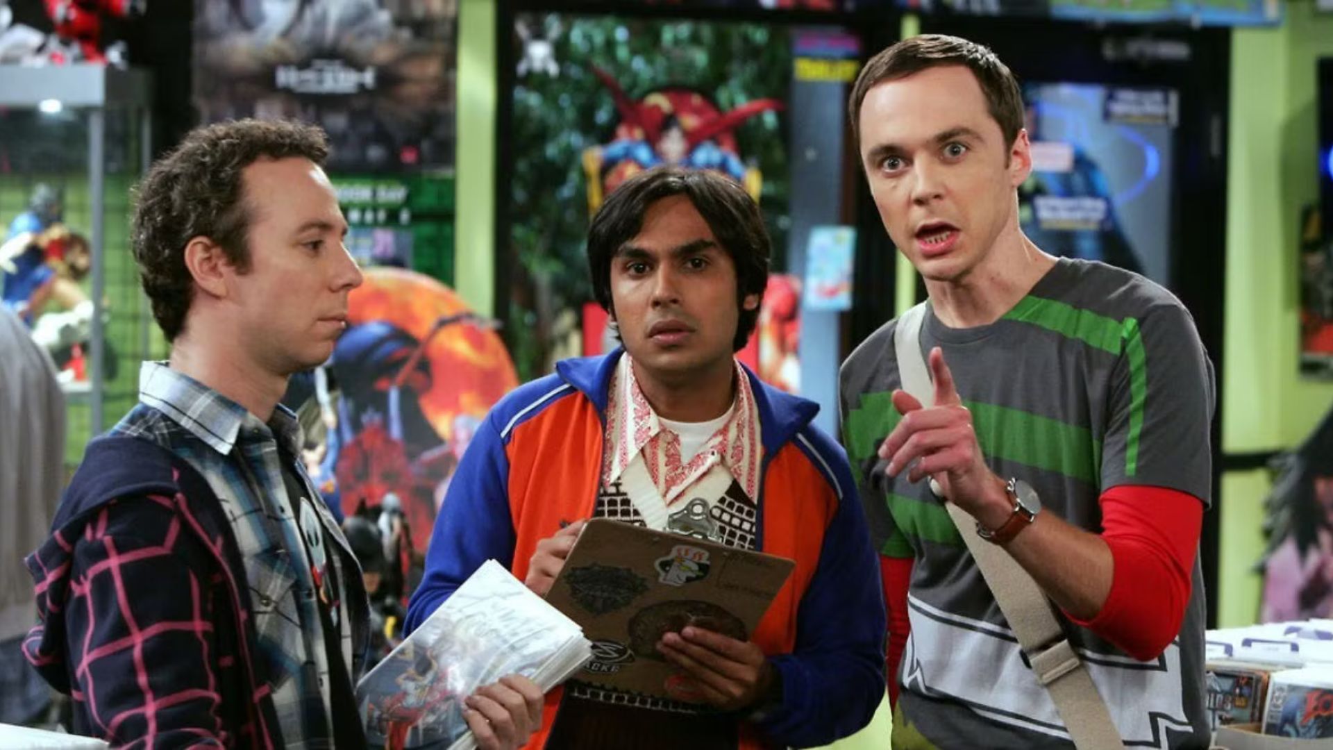 Sheldon points to something off screen while Raj stares intently while Stuart looks straight into space