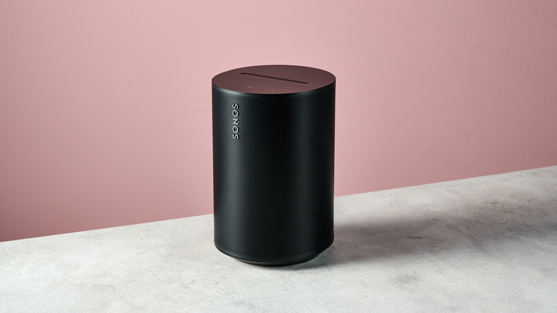 Sonos Era 100 SL in a 3/4 angle in front of a pink background.