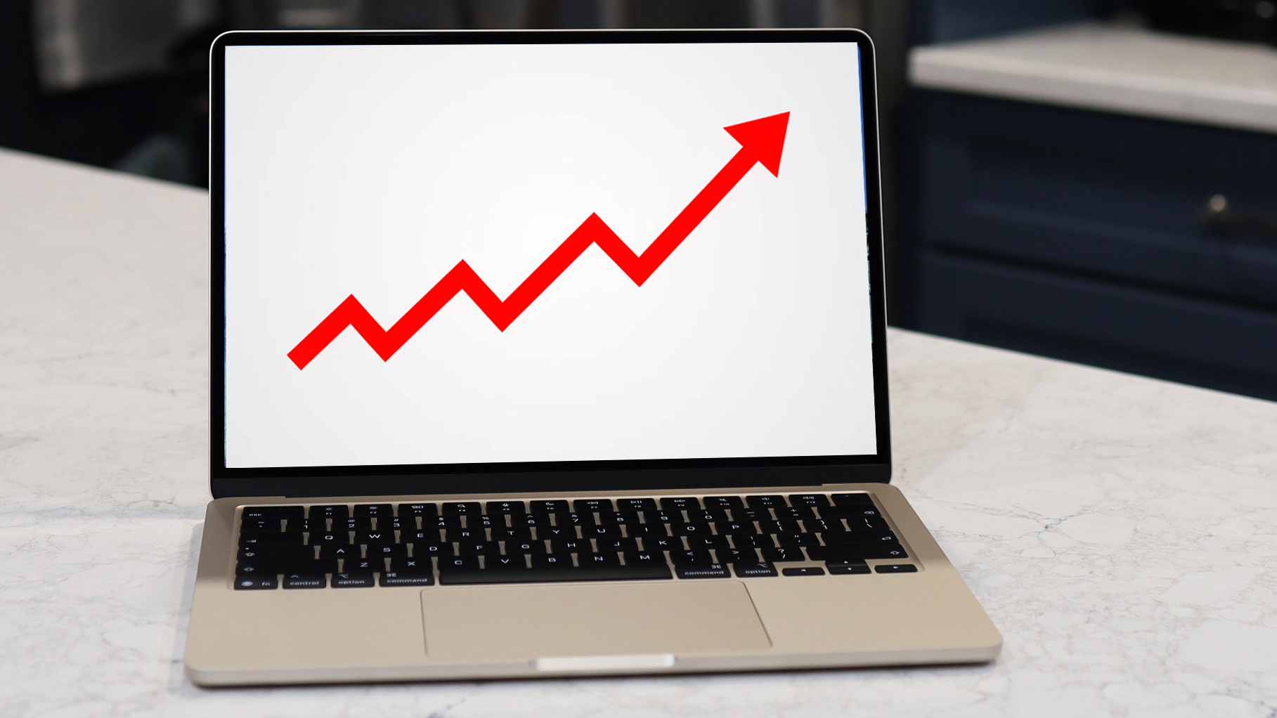 A MacBook screen shows a red arrow rising