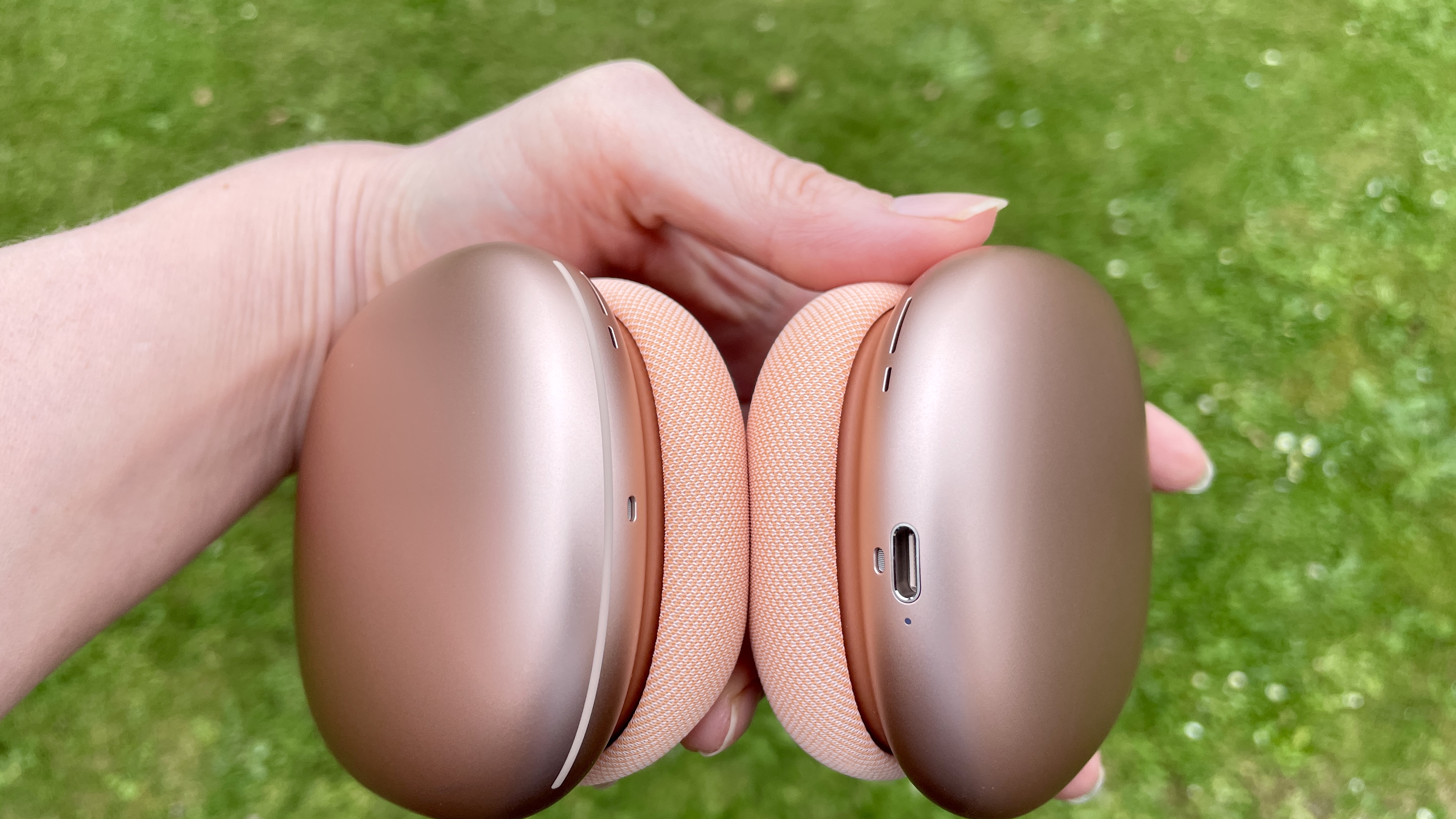 AirPods Max 2 in a garden, held by hand, close-up to show the ear cups and band