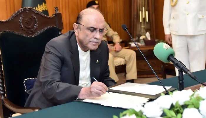 President Asif Ali Zardari signs a bill into law in this undated photo. — The President's House