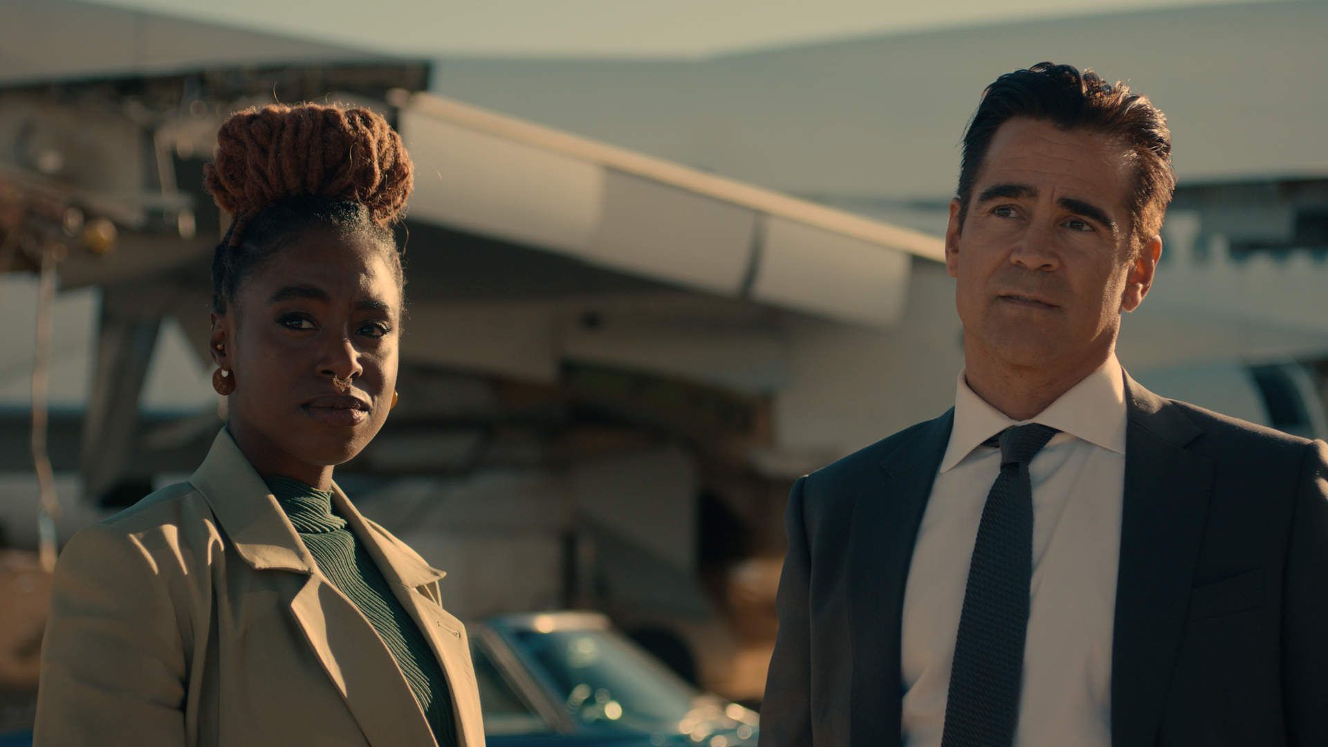 Kirby Howell-Baptiste and Colin Farrell's characters stand next to each other in Apple TV Plus' Sugar Show