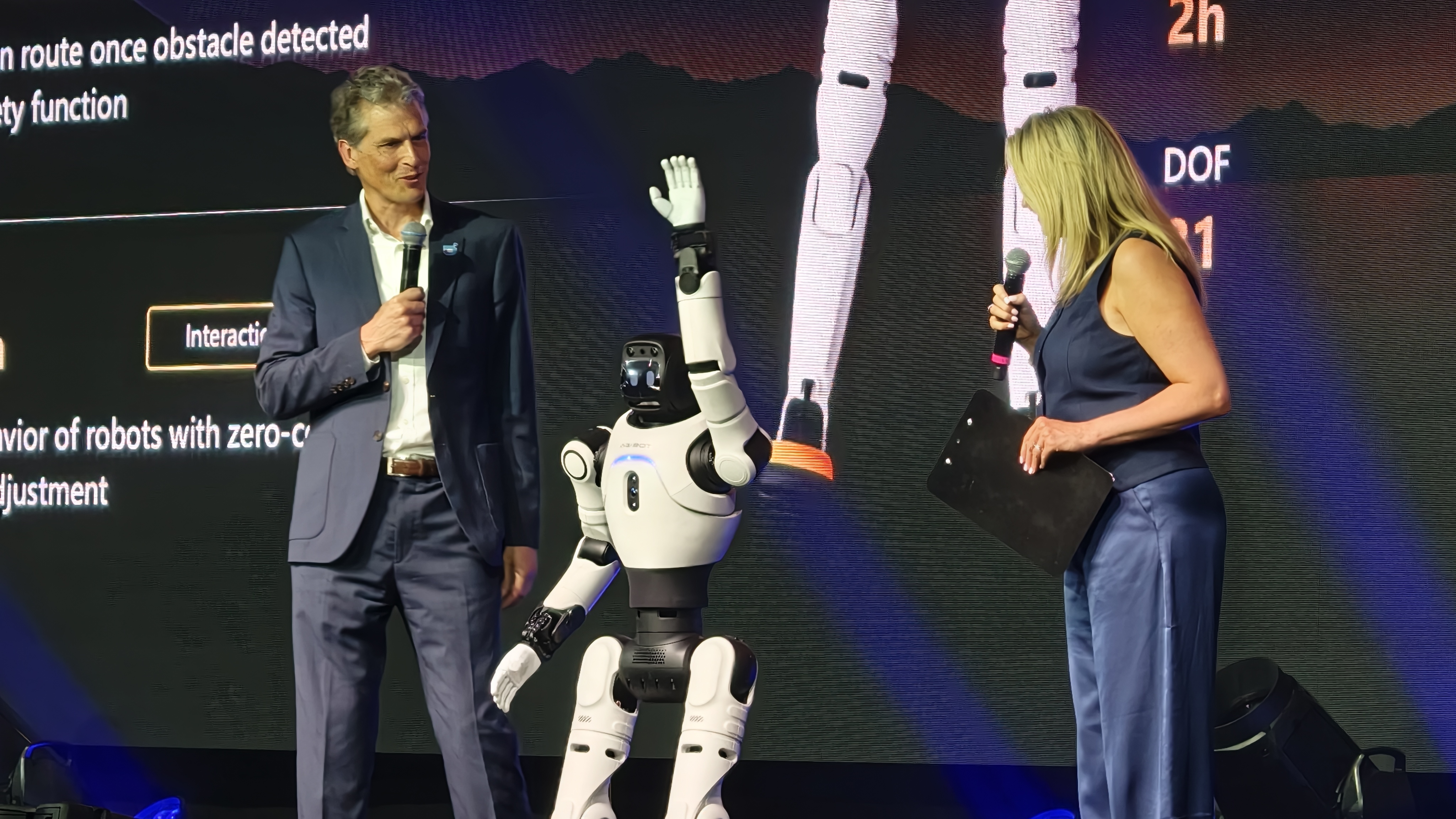 An AGIBOT X2 robot waves to the audience on stage
