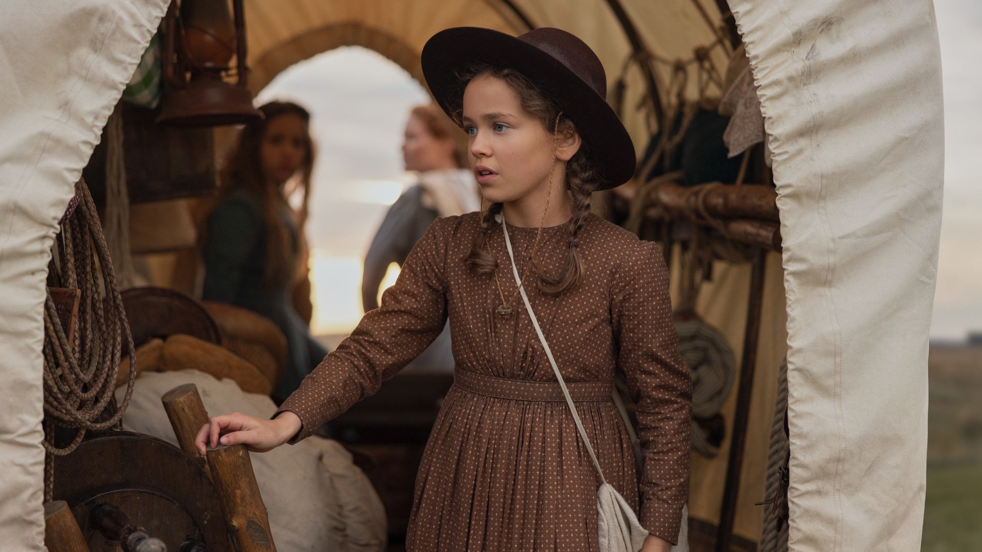 Laura is standing in the back of a carriage