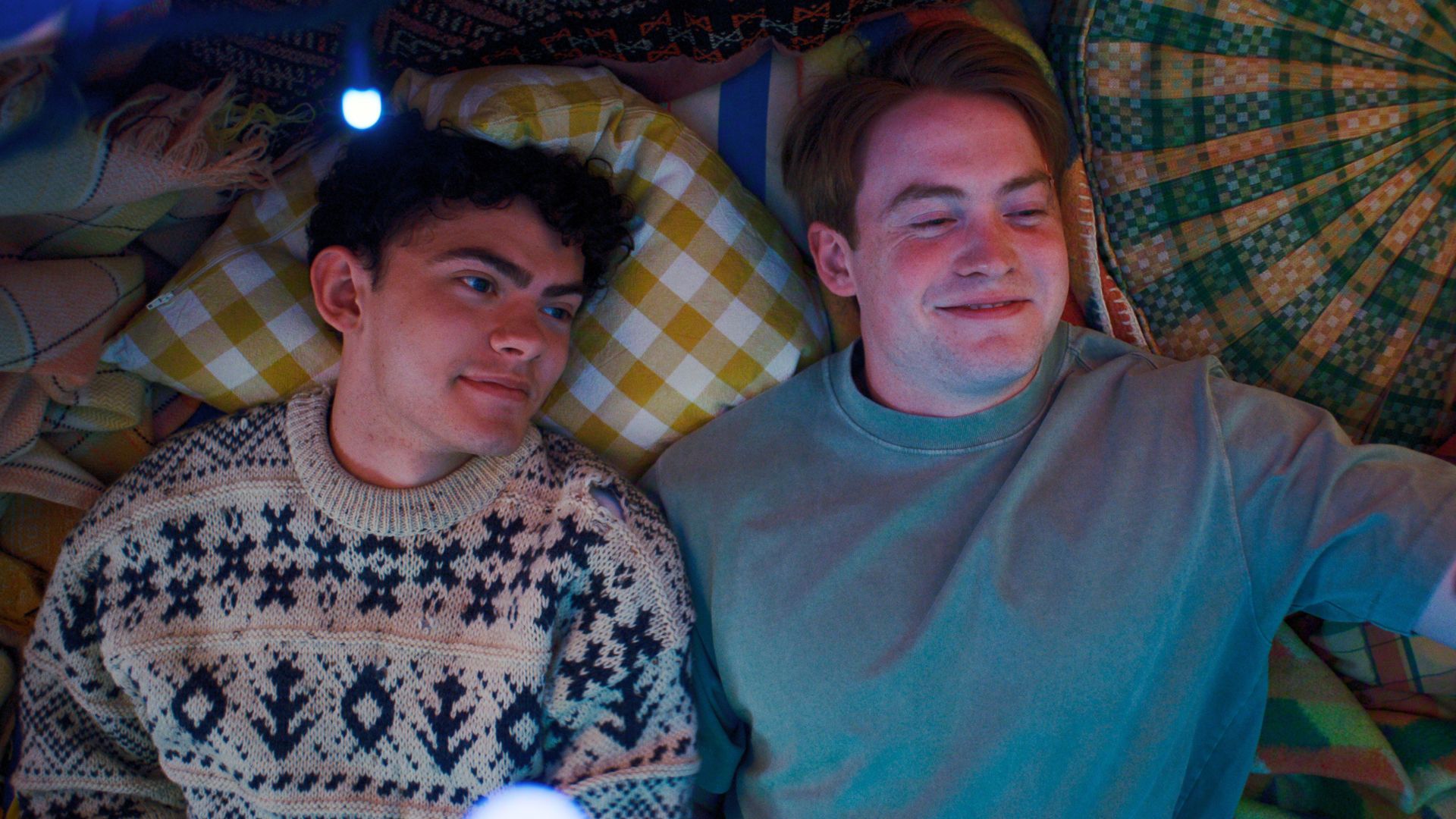 Nick and Charlie are lying on a bed