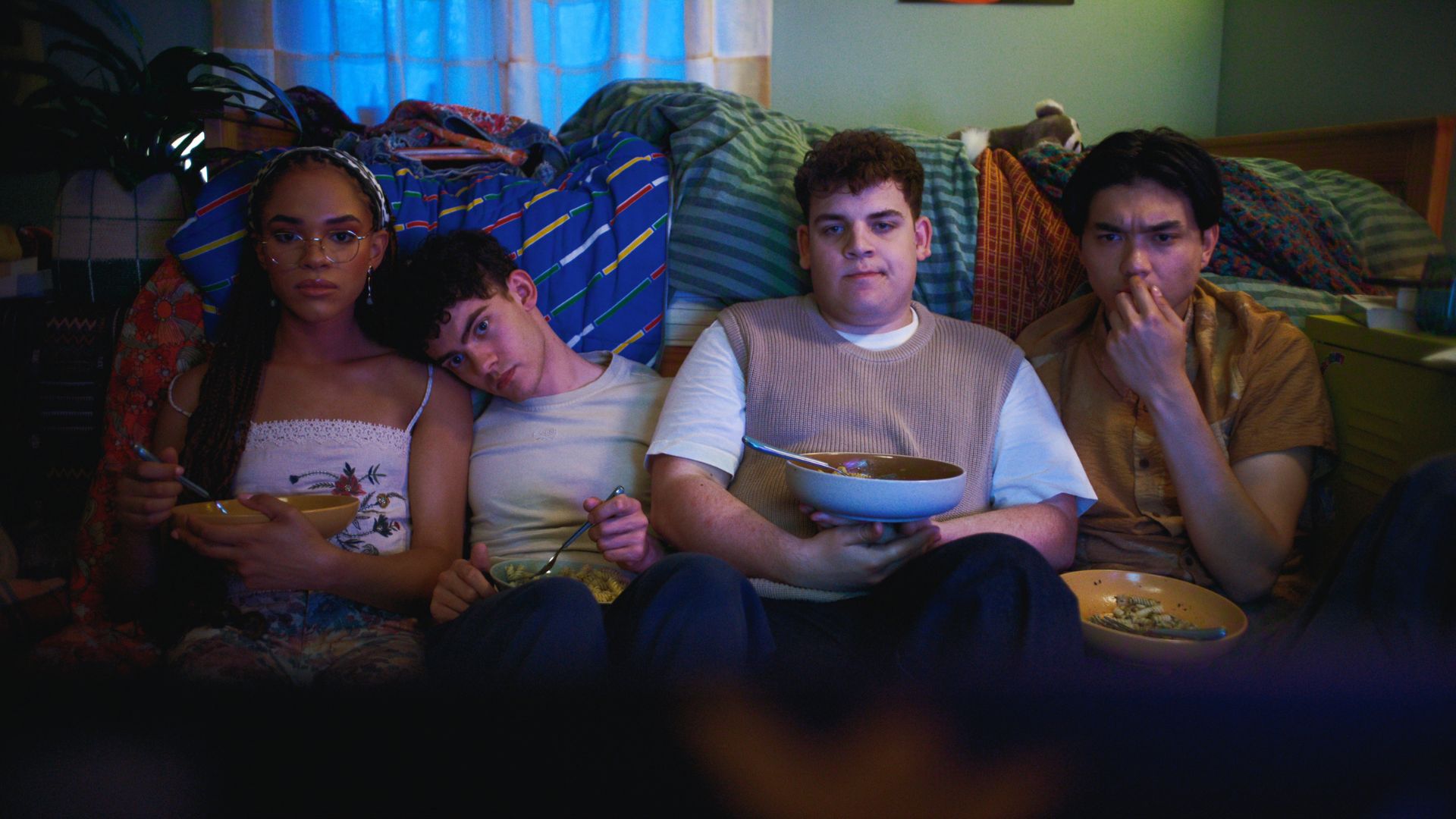 Elle, Charlie, Isaac and Tao are sitting on the bedroom floor eating pasta