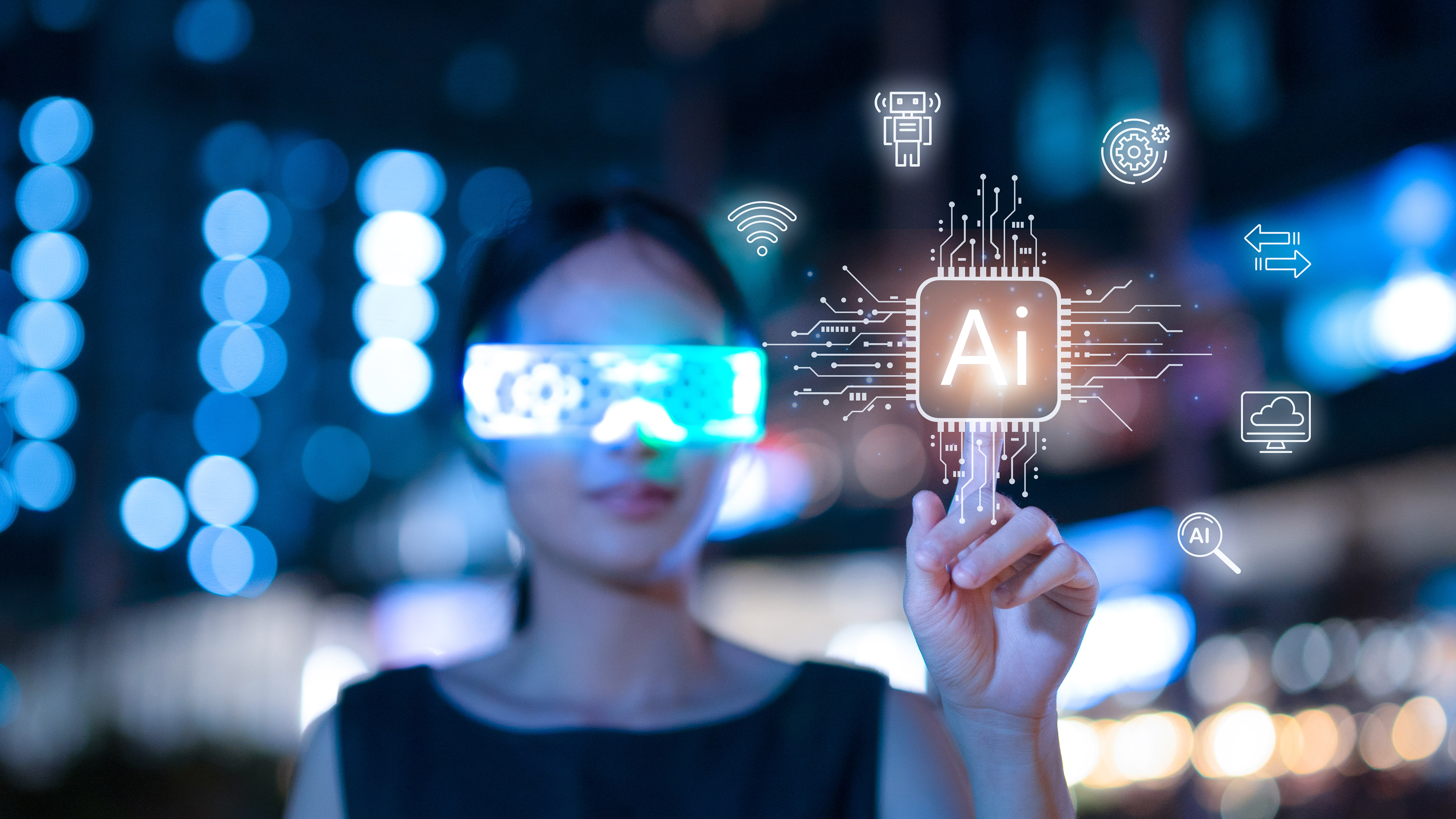 An out-of-focus woman in the background touches the word AI, illuminated in glowing yellow light, in the foreground. The woman is wearing smart glasses