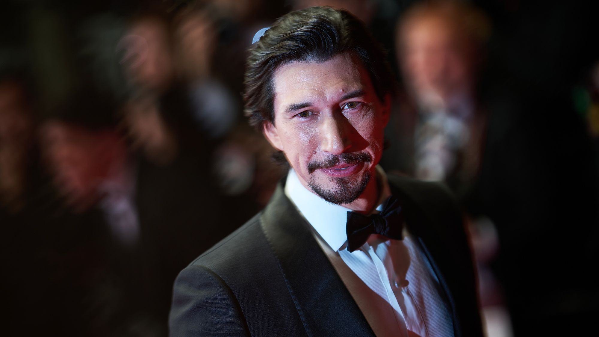 Adam Driver smiles while wearing a tuxedo during an event