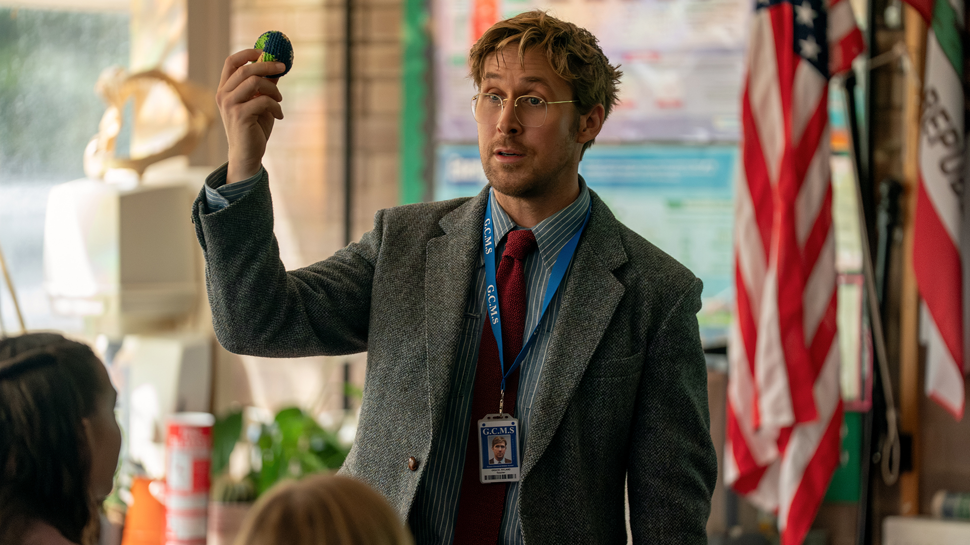 Ryland Grace holds up a knitted earth in front of some school children in Project Hail Mary